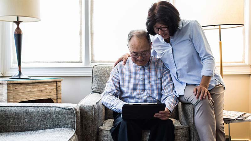Senior couple looking at the tablet while sitting inside the home