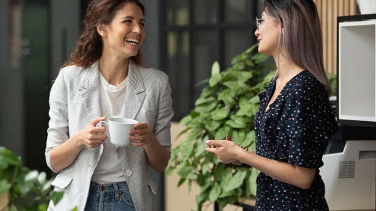 two women employees standing and talking while laughing